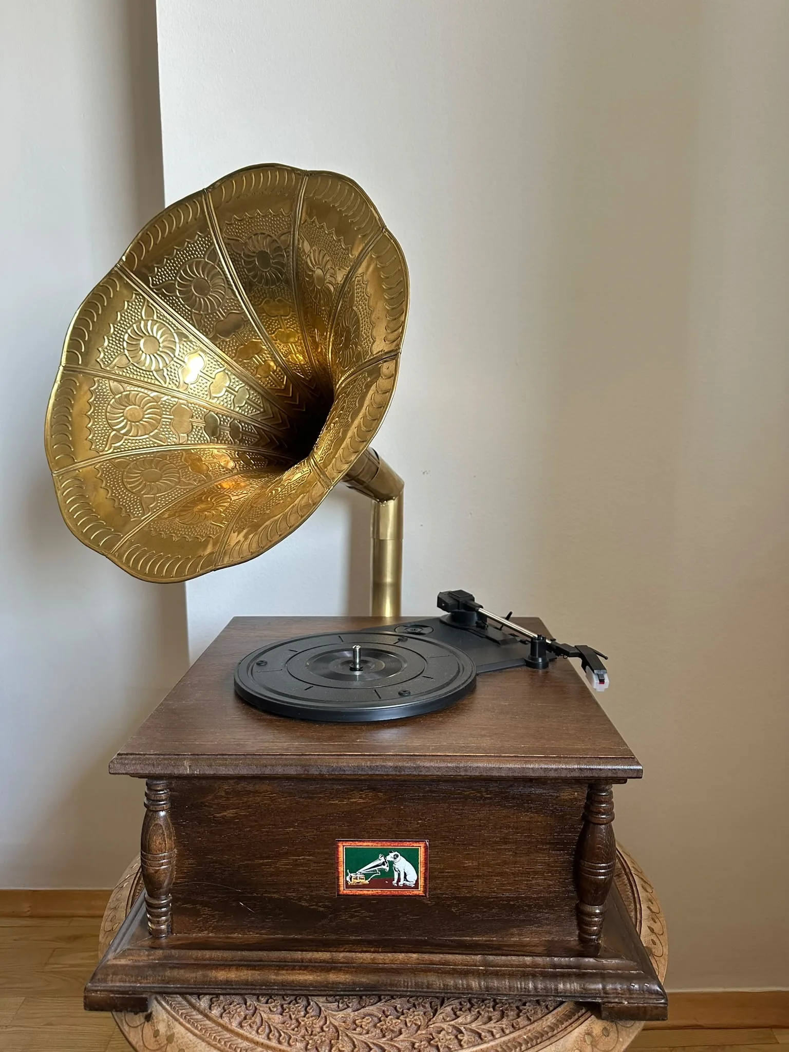 A raw phone photo of an antique brass gramophone against a plain wall, the source image for the pipeline